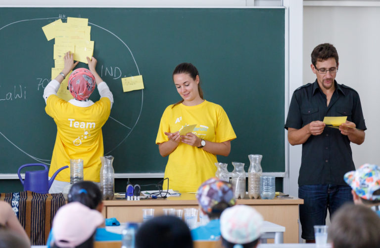Freiwillige Mitarbeiterinnen helfen einem Lehrenden in einer Lehrveranstaltung