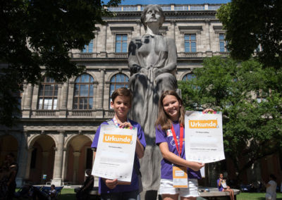 Children with certificates in the arcade courtyard