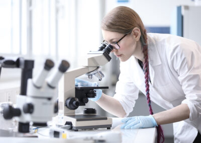 Woman in white lab coat microscope