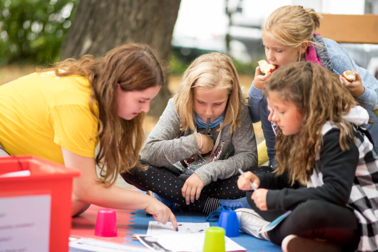 Group of girls and team member reading experiment instructions