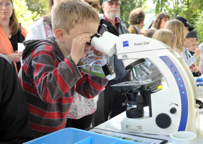 Kind betrachet eine Probe im Mikroskop