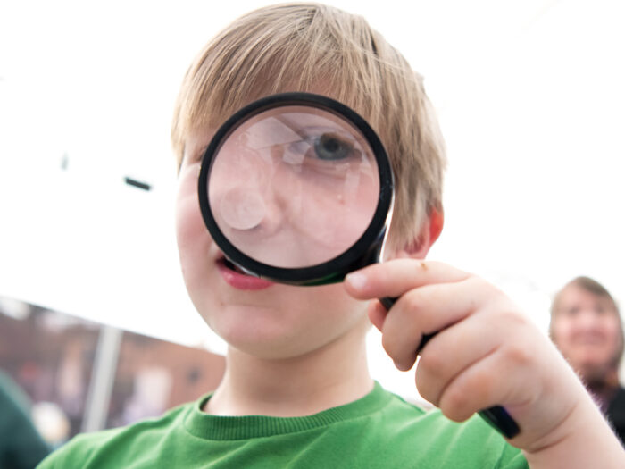 A child looks through a magnifying glass