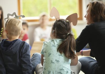 Kinder mit gebastelten Tierohren im Sitzkreis