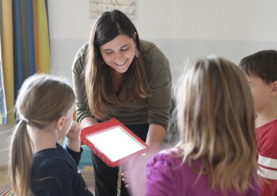 Pädagogin zeigt Kindern das Tablet