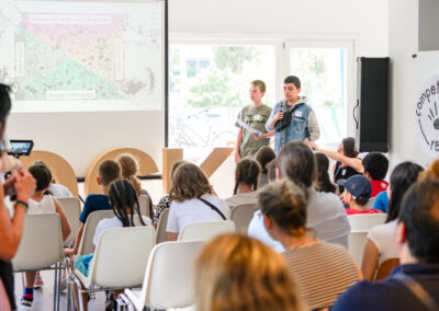 Zwei Jugendliche zeigen eine Präsentation vor einem Publikum.